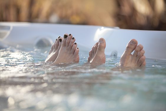 a close-up image of a couples toes peaking out of the water in a portable hot tub