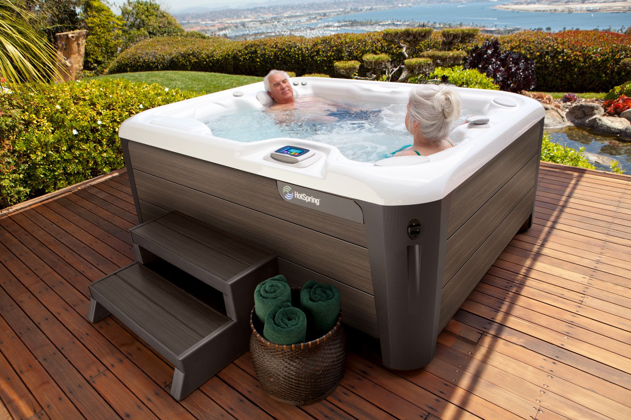 An older couple enjoying a peaceful moment together in a two-person hot tub, with the stunning ocean as a backdrop.