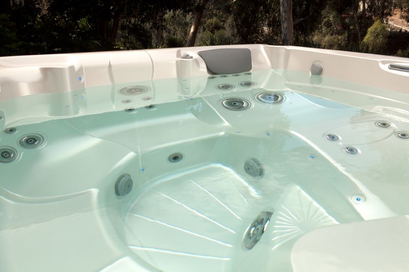 Close-up view of an empty modern hot tub with multiple jets and ergonomic seating