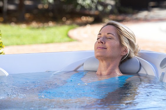 a woman takes a relaxing soak in a hot spot rhythm jacuzzi on a beautiful day